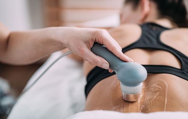 Doctor using ultrasound therapy machine at family chiropractor